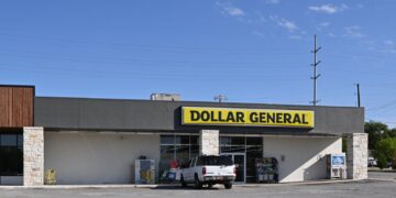 A Dollar General store with its yellow and black sign, a white SUV parked out front, in Sapulpa, Oklahoma