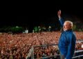 Luiz Inácio Lula da Silva raises his hand to a large nighttime crowd from a stage in São Paulo
