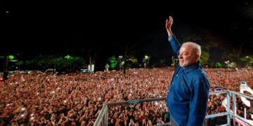 Luiz Inácio Lula da Silva raises his hand to a large nighttime crowd from a stage in São Paulo