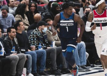 Minnesota Timberwolves guard Anthony Edwards, wearing No. 1 in a navy Minnesota jersey, runs up the court beside Washington's Kentavious Caldwell-Pope