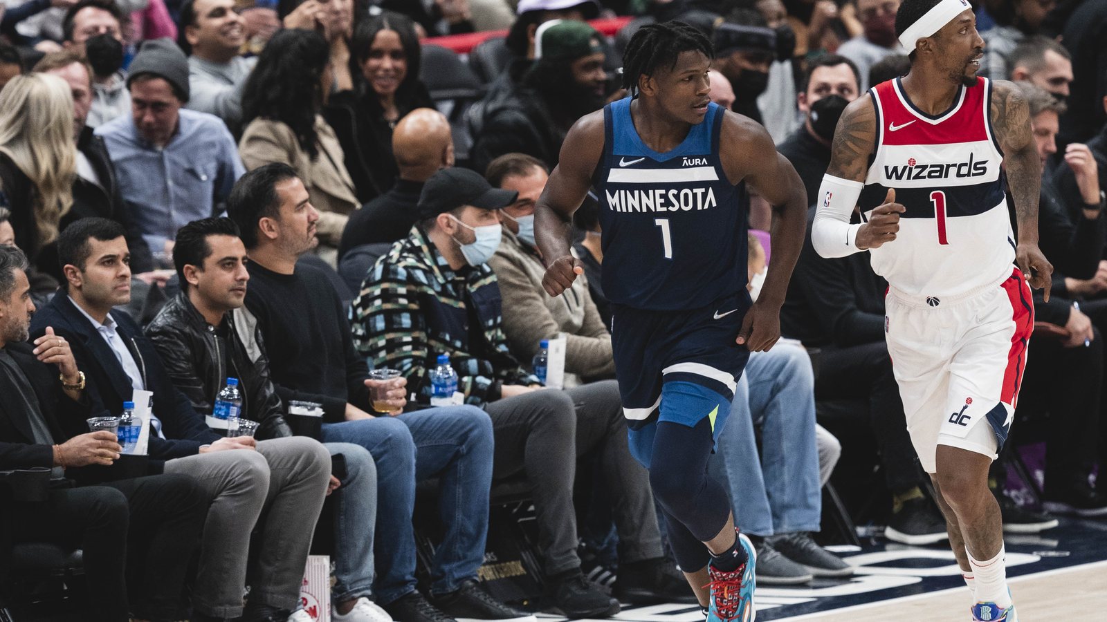Minnesota Timberwolves guard Anthony Edwards, wearing No. 1 in a navy Minnesota jersey, runs up the court beside Washington's Kentavious Caldwell-Pope
