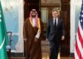 Saudi Defense Minister Prince Khalid bin Salman in a red-checked headdress and brown robe walks beside Antony Blinken at the State Department