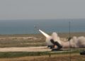 A US Army Patriot launcher fires a missile on a coastal range as smoke billows around it
