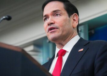 Secretary of State Marco Rubio, in a dark suit and red tie, speaks at the White House briefing room podium