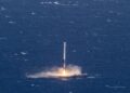 A rocket booster fires its engine as it lands upright on a drone ship in the open ocean