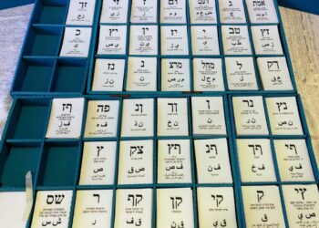 Trays of white paper ballot slips, each printed with a party's Hebrew letters, inside an Israeli voting booth