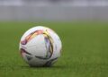 A soccer ball resting on a grass pitch