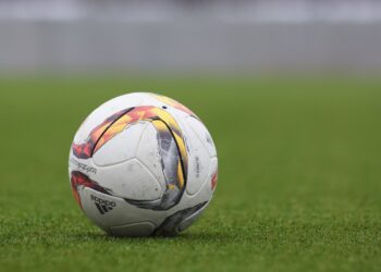 A soccer ball resting on a grass pitch