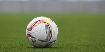 A soccer ball resting on a grass pitch