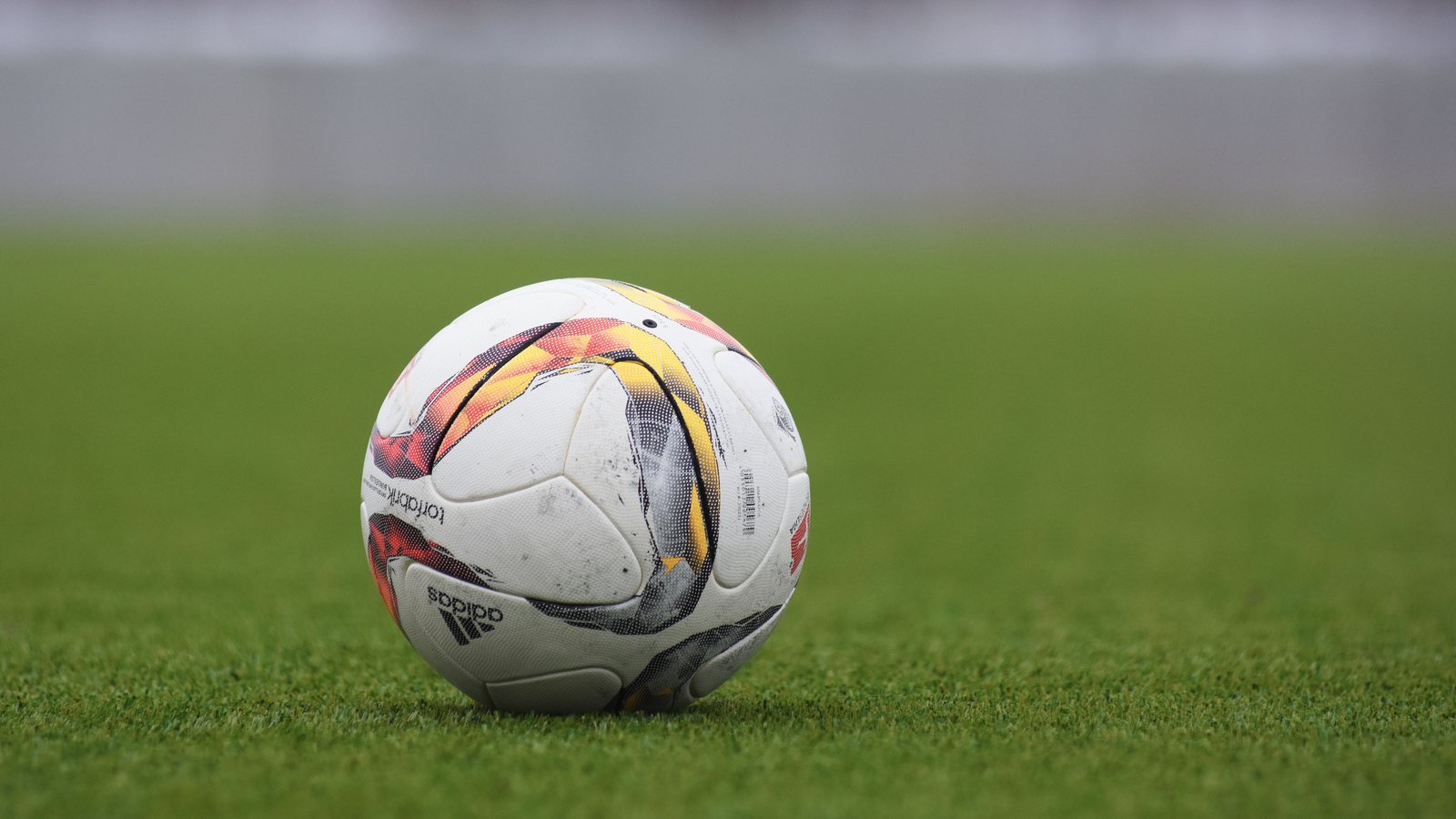 A soccer ball resting on a grass pitch