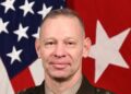 Lt. Gen. Brett Sylvia in Army dress uniform in his official portrait, in front of a US flag and a red general's flag