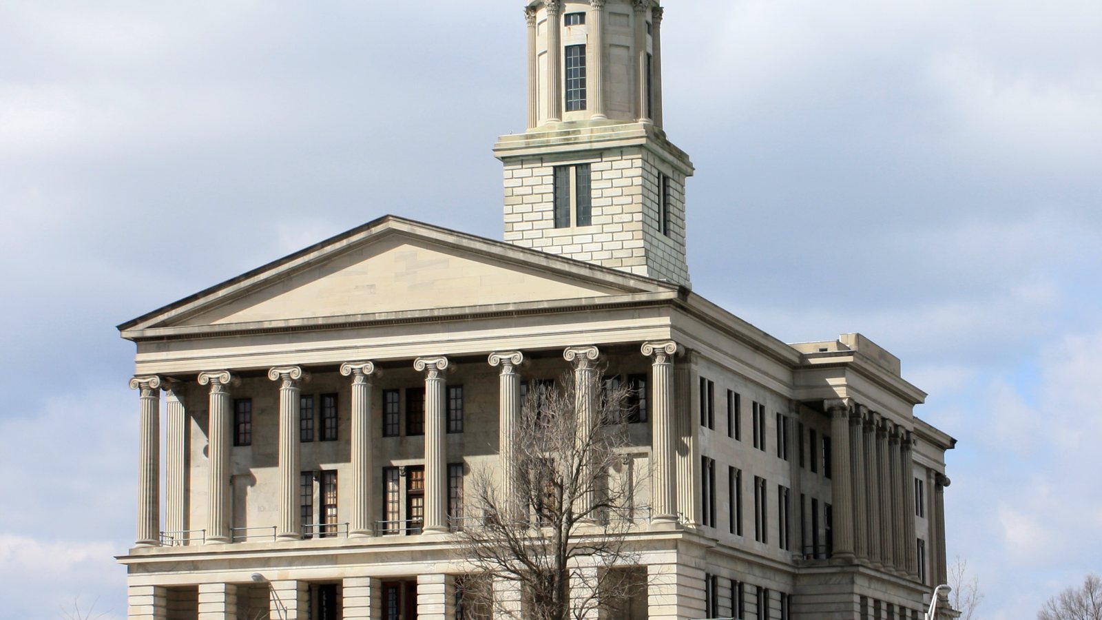 The Tennessee State Capitol in Nashville, a columned limestone building with a central tower, under a cloudy sky