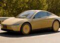 A gold Tesla Cybercab, a two-seat car with no steering wheel, driving on Interstate 280 near Palo Alto, California