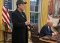 Elon Musk stands in the Oval Office while President Donald Trump sits at the Resolute Desk