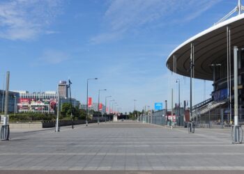 The curved roof and empty forecourt of Stade de France in Saint-Denis, north of Paris, on a sunny day