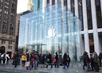 Shoppers walk past the glass cube entrance of Apple's Fifth Avenue store in New York