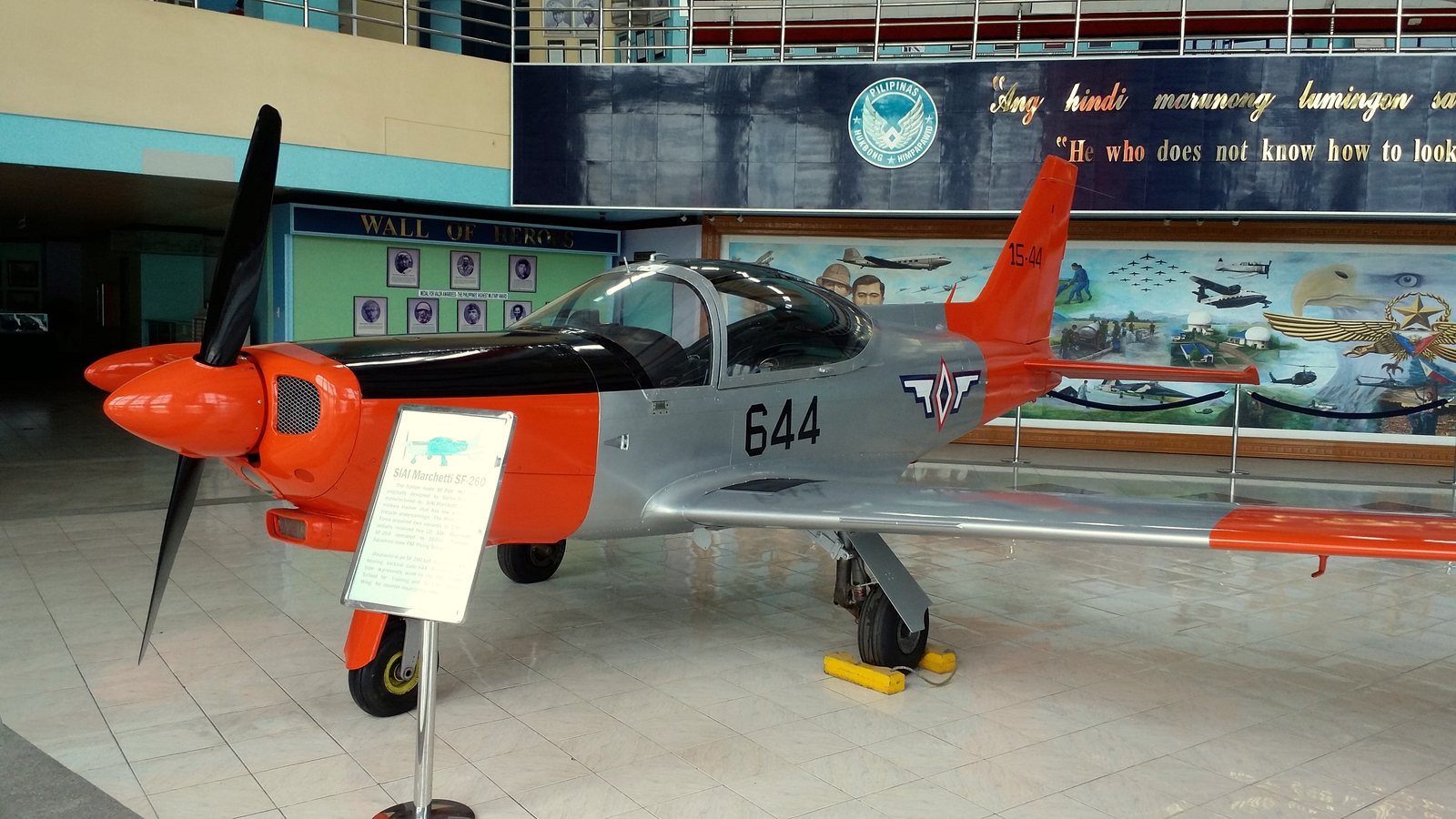 A silver and orange Philippine Air Force SF-260 trainer aircraft on display indoors at the PAF Aerospace Museum