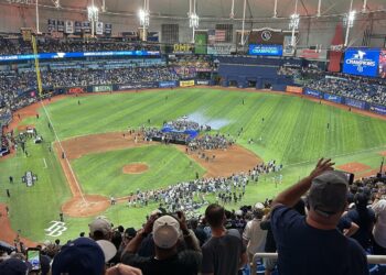 Fans in the upper deck at Tropicana Field watch the Rays' American League championship trophy ceremony on the infield, with American League Champions graphics on the stadium video boards