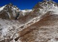Rocky mountain slopes lightly dusted with early-season snow under a deep blue sky at Twin Peaks above Eklutna Lake, Alaska