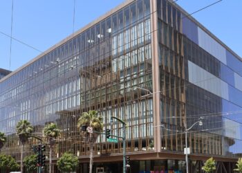 A glass-fronted office building lined with palm trees at 1515 Third Street in San Francisco's Mission Bay, under a blue sky