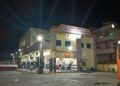 The Uttar Pradesh state bus station in Mau, India, lit up at night with a red bus parked outside