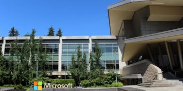 The Microsoft logo sign in front of Building 92 on the company's campus in Redmond, Washington, under a clear blue sky