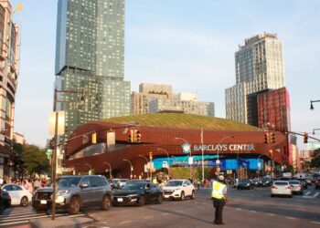 Barclays Center, home of the NBA's Brooklyn Nets, seen from a busy Brooklyn intersection with apartment towers behind it