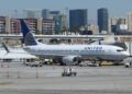 A white United Airlines Boeing 737 with a blue globe tail parked at a gate at the Las Vegas airport, with Strip hotel towers behind it