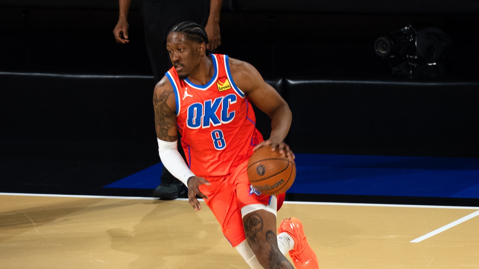 Oklahoma City Thunder forward Jalen Williams, in an orange OKC jersey, dribbles the ball up the court during an NBA Cup game