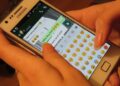 Hands typing a WhatsApp message on a smartphone
